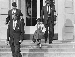 William Frantz Elementary School, New Orleans, 1960. "After a Federal court ordered the desegregation of schools in the South, U.S. Marshals escorted a young Black girl, Ruby Bridges, to school." Note: Photo appears to show Bridges and the Marshals leaving the school. She was escorted both to and from the school while segregationist protests continued.